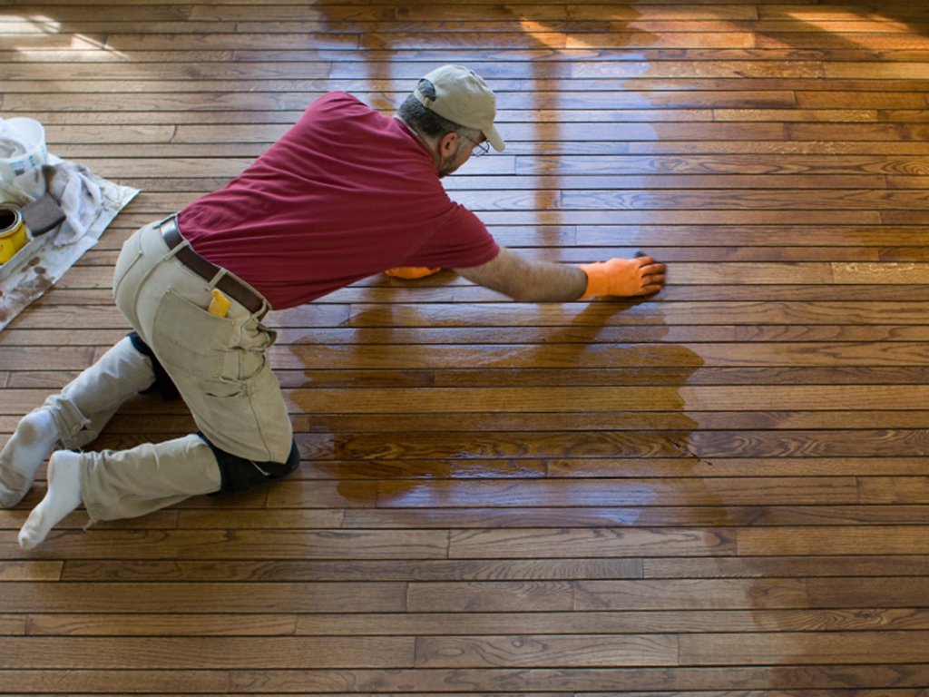 a technician in the process of refinishing a hardwood floor